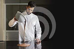 Pastry chef working on tempering chocolate on marble table photo