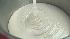 Pastry cook pours thick white cream in a bowl