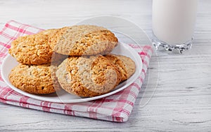 Pastry cookies on a white wooden board and a glass of milk