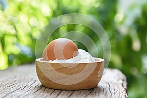 Pastry flour on wooden bowl nature green background - homemade flour egg cooking ingredients on table