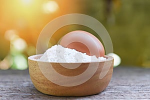 Pastry flour on wooden bowl nature green background - homemade flour egg cooking ingredients on table