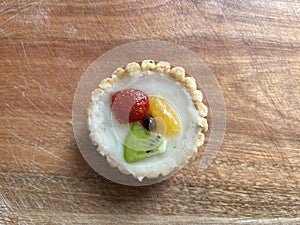 Pastry sweet pie with some fruit on wooden background.