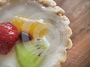 Pastry sweet pie with some fruits on wooden background