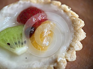 Pastry sweet pie with some fruits on wooden background