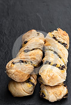 Pastry twist with a custard and dark chocolate chip filling on black stone background