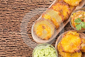 Patacon fried pieces of crushed green banana. Guacamole. On the wooden table toston, tachino