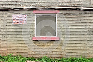 Patched green painted old brick wall with window centered