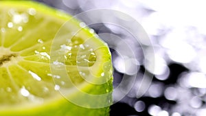 Patches of light of drops of water at a background. Drops of water fall on the cut lime on a black background. Limes Cut