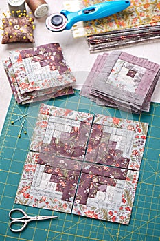 Patchwork log cabin blocks on craft mat, stack of blocks, sewing accessories