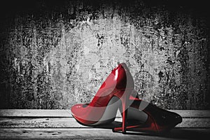 Patent shiny womens red stiletto heels on table by old wall