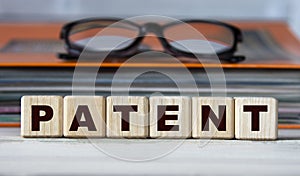 PATENT - word on wooden cubes on the background of a folder with documents and glasses
