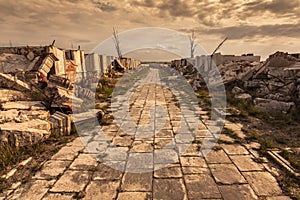 Path between demolished buildings with expressive sky and dry trees. Abandoned cemetery in CarhuÃÂ©, Buenos Aires, Argentina. photo