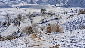 The path descends from the snow-covered hillside.