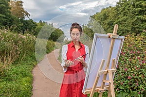 path into distance bushes grass, woman artist in summer in park, draws picture. Free space copy text. Creation of