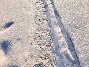 A path with fresh footprints in the snow in winter
