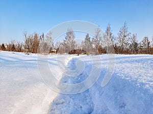 A path with fresh footprints in the snow in winter