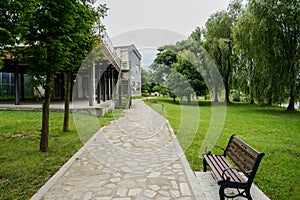 Path in lawn before two-storied building with terrace in cloudy