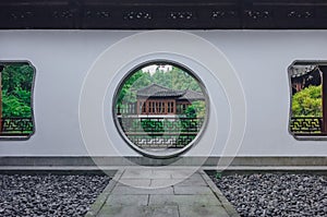 Path leading to moon gate with view of traditional Chinese building, in a Chinese garden, near West Lake, in Hangzhou, China