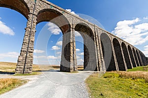 Path leading to sunlit arches of a railway viaduct