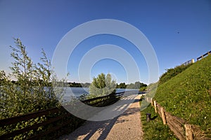 Path in a park by the shore of a lake in an italian town at sunset