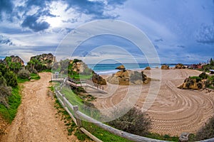 The path among the rocks and green hills leading to the famous beach in Alvor, Algarve, Portugal.