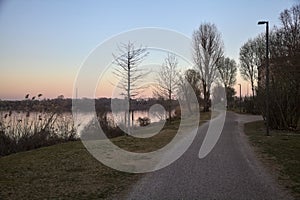 Path by the shore of a lake in a park at dusk