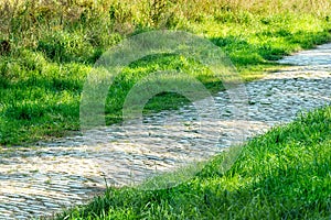 Path or sidewalk made with rock blocks near lawn. straight pathway in the midst of grassland. pebble walk way in backyard. old