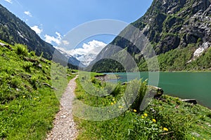 Path through spring mountains landscape near alpine lake. Stillup, Stillup Lake, Austria