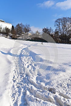 The path trodden in the snow drifts to the city and hotel building