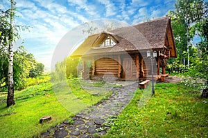 Path and wooden house in a birch grove on summer day