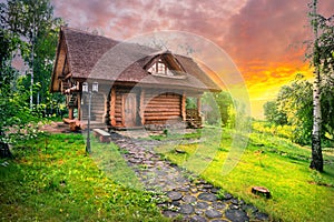 Path and wooden house in birch grove under dramatic sunset skies