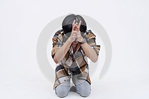 A pathetic and fearful young asian man bowing down and begging to be spared. Isolated on a white background