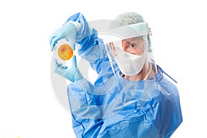 Pathology sceintist in biosecurity suit and PPE holds up a petri dish