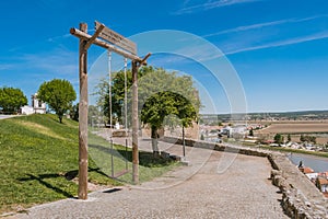 Pathway in the castle with a swinging wood structure with a phrase alluding to Alcacér do Sal, PORTUGAL