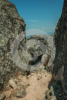 Pathway encircled by big rocks and dry bushes on hilltop