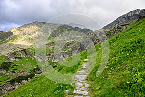 Pathway made of stones through green hill in mountains