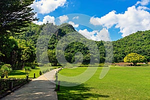 Pathway passes through lush grassy fields amidst a beautiful tranquil nature with the mountains in background. Beautiful view of