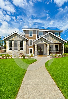 Pathway to Ideal residential house in perfect neighbourhood. Family house with big green lawn in front on blue sky background