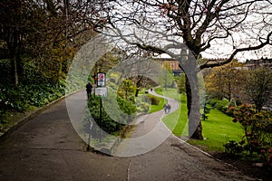 Pathways in Prince Street Gardens, with People walking along the gardens during a rainy day in spring. Edinburgh