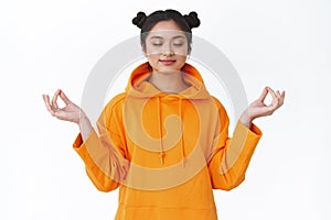 Patience is key. Happy and calm, relaxed smiling asian girl meditating in lotus pose with gen gesture, close eyes and