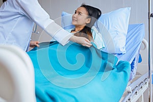 Patient asian woman on sickbed with doctor standing and putting blanket on her,Happy and smiling