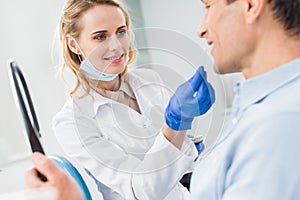 Patient choosing tooth implant looking at mirror in modern