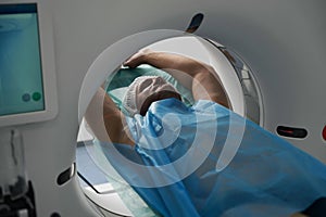 Patient with closed eyes lies in chamber of the tomograph