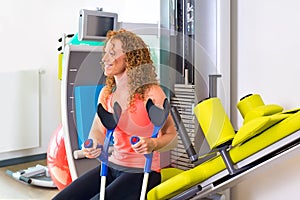 Patient with crutches sitting on weight machine