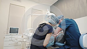 The patient, dentist and assistant in office of a dental clinic