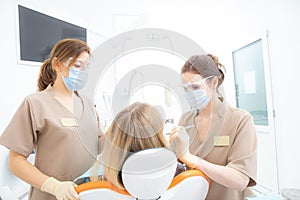 Patient with dentist and dental assistant wearing masks and gloves.