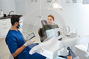 Patient and dentist are discussing teeth image on digital tablet