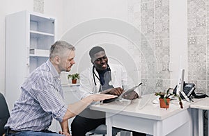 the patient and the doctor carefully study the results of the examination sitting at the table in the medical center.