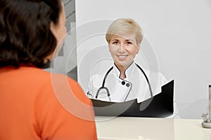 Patient and doctor holding folder behind reception.