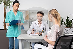 Patient with doctor and internist sitting at table during consultation in clinic photo